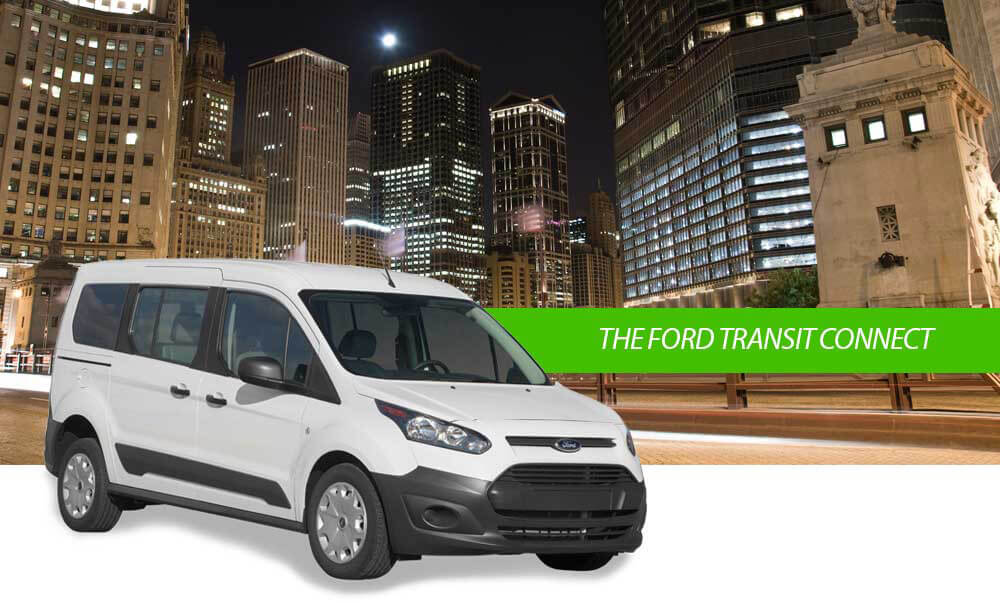 white Ford Transit Connect in front of a night cityscape